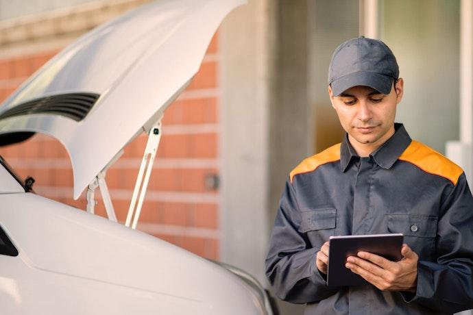 Homme tenant une tablette devant une camionnette